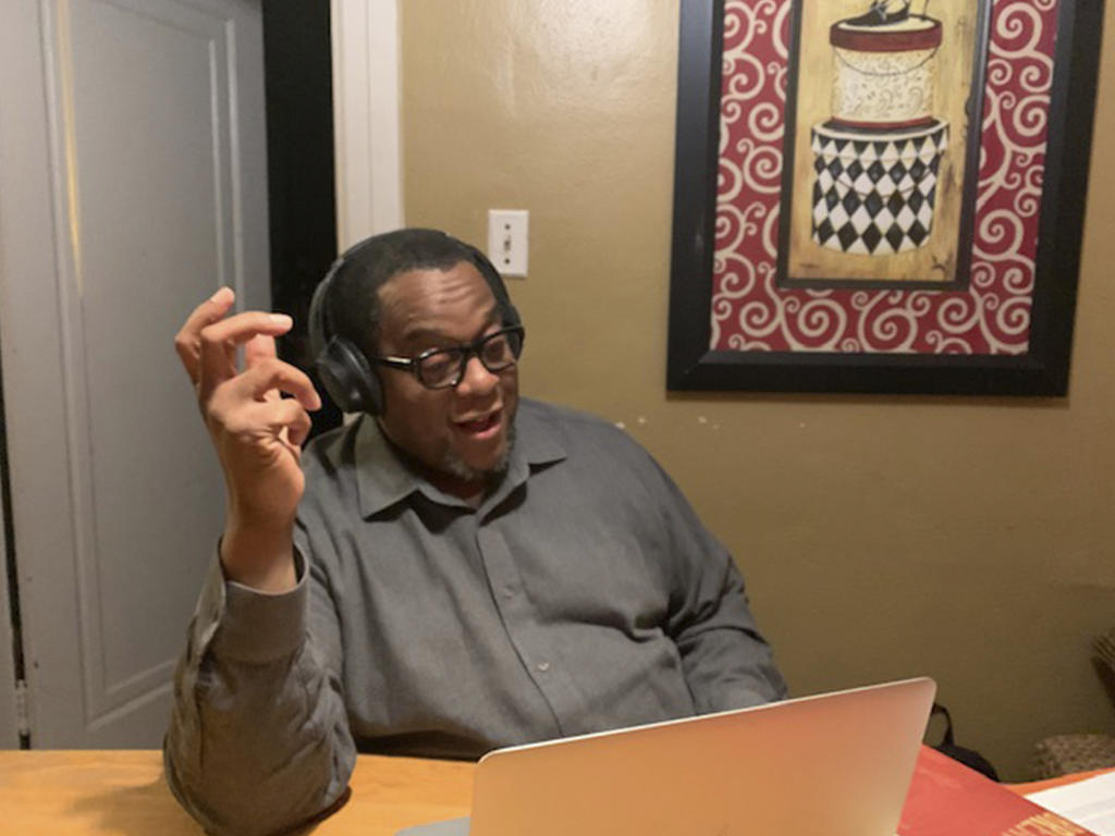 an African American man with headphones talks to a video audience