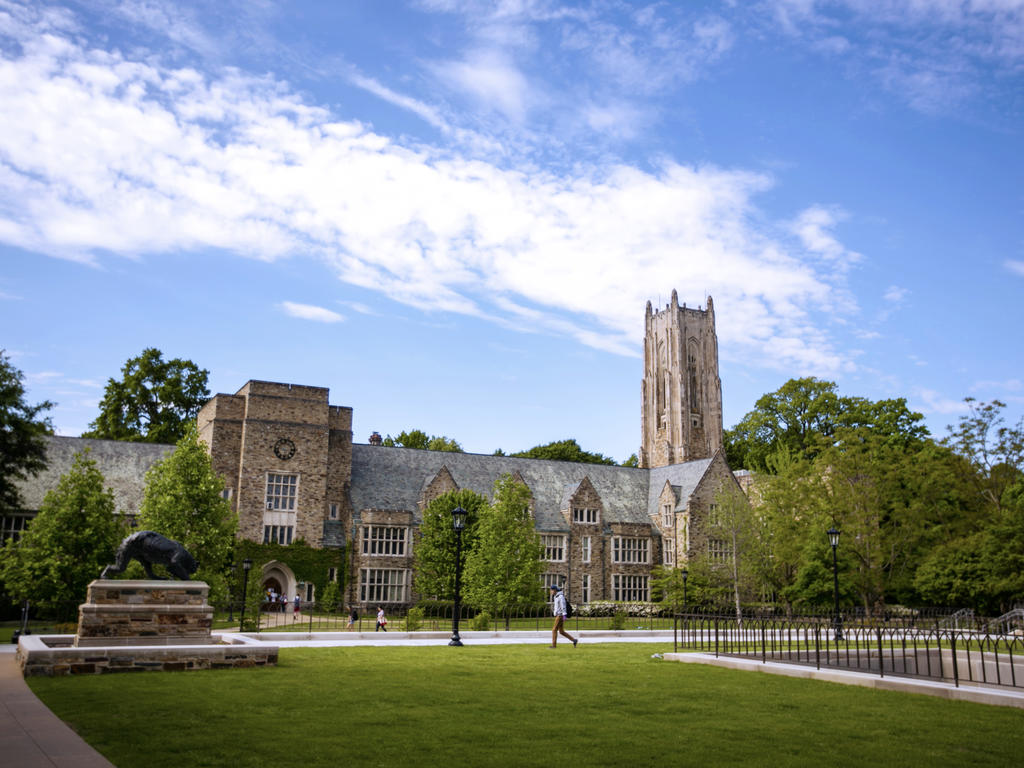 Collegiate Gothic building with grass, trees, and a statue of a lynx