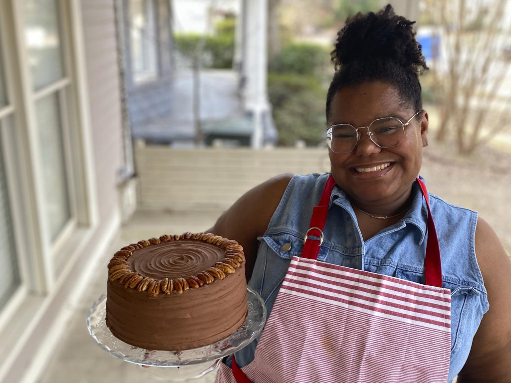 a young  African American woman holds a cake