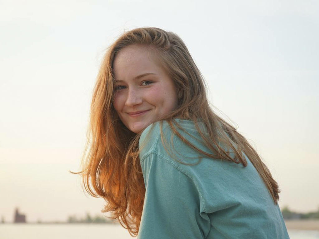 a young woman with long red hair looks at the camera