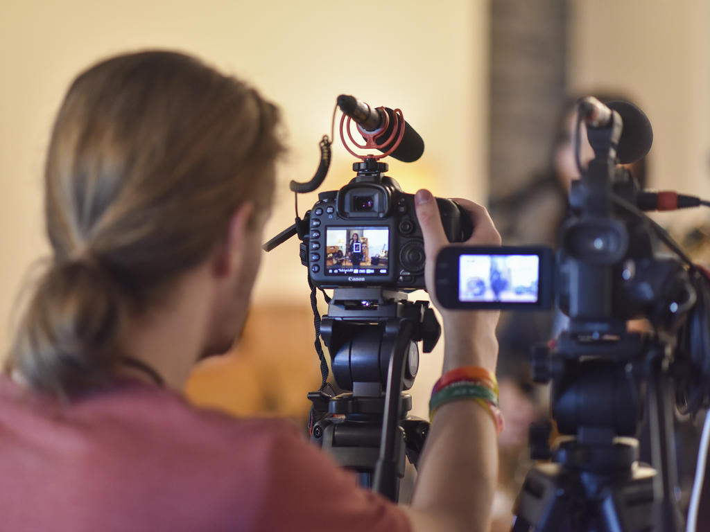 a young man looks through a viewfinder of a video camera