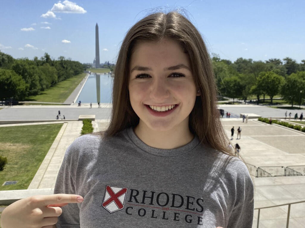 a young woman in a Rhodes t-shirt in front of the Washington Monument