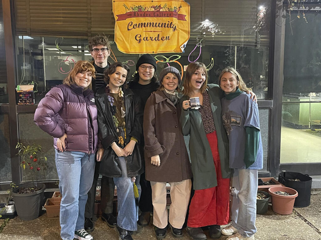 a group of students pose in front of a Community Garden sign