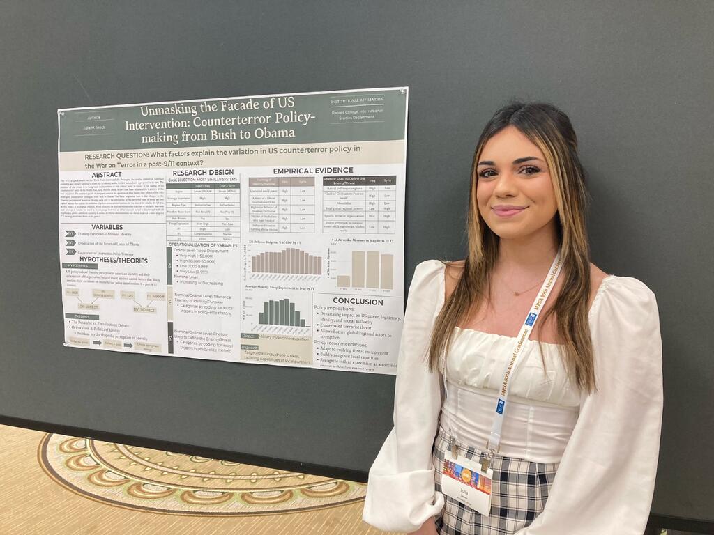 image of Rhodes College student Julia Seeds standing next to a research poster