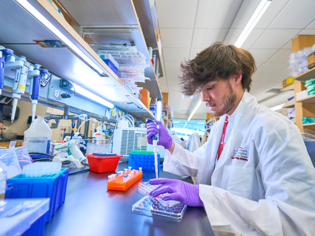 a young man in a lab coat works with a pipette