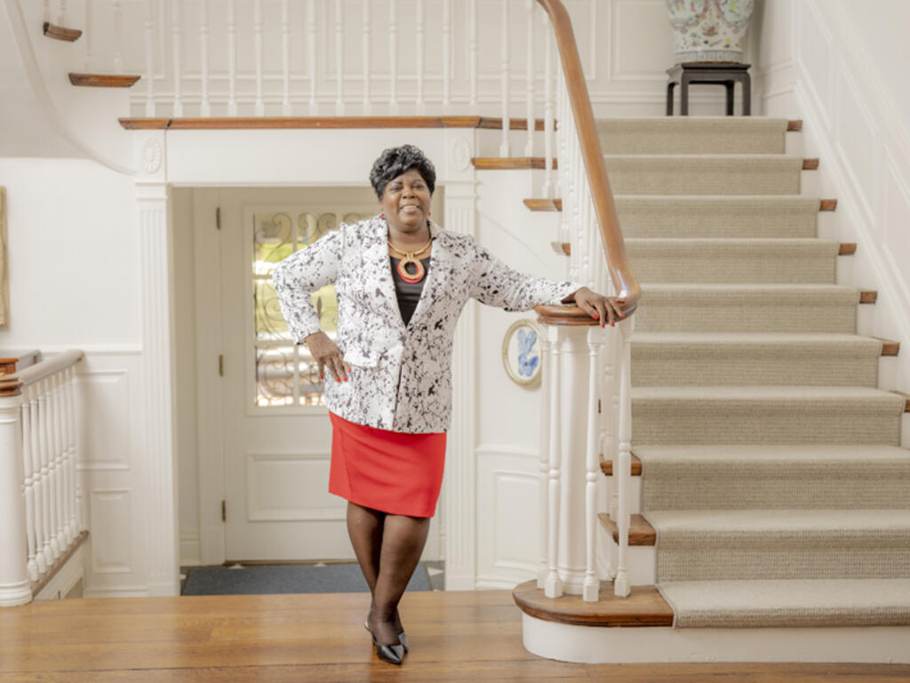 an African American woman stands in the threshold of a large house