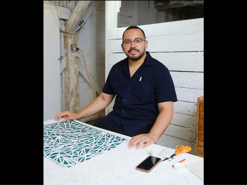 image of artist Johnathan Payne at desk with artwork