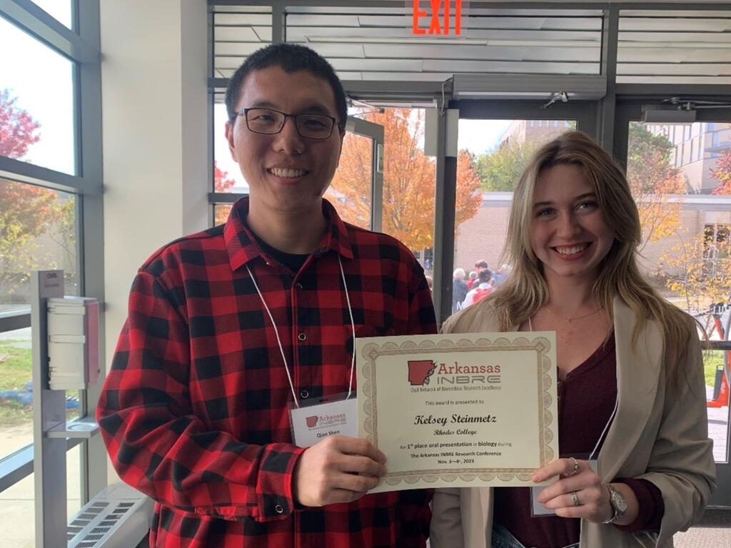 Image of Rhodes College professor standing next to student holding award certificate