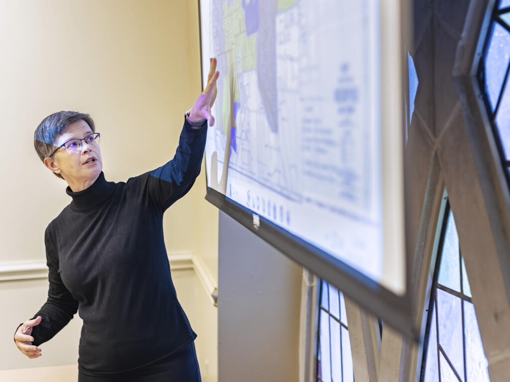 a female professor points at a projected slide