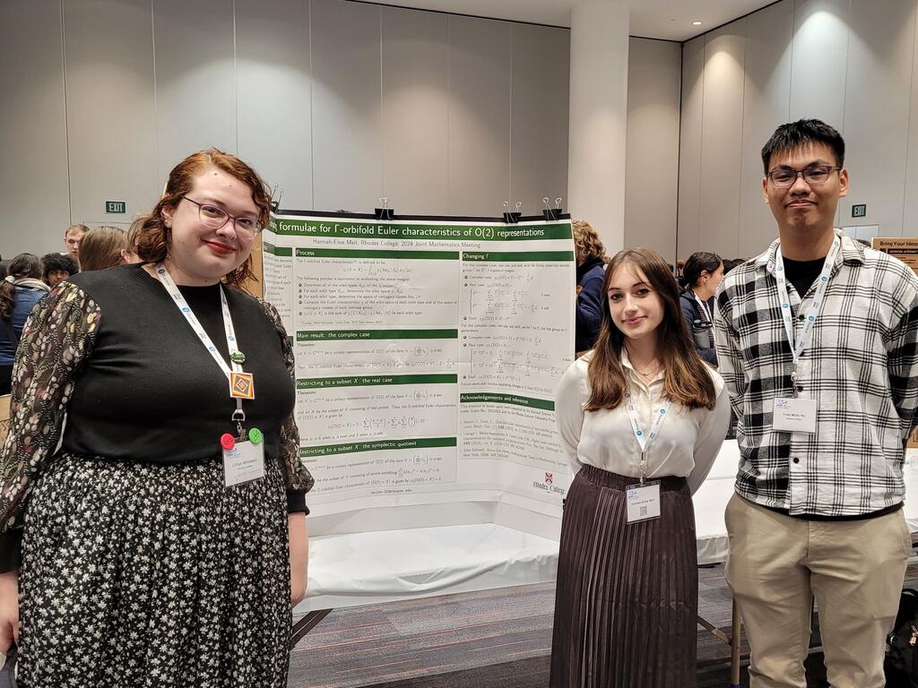 image of three Rhodes College students standing in front of a poster