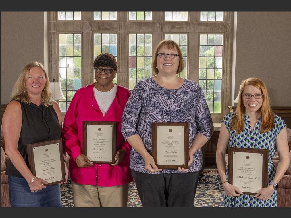 group image of four Rhodes College staff, each holding a plaque