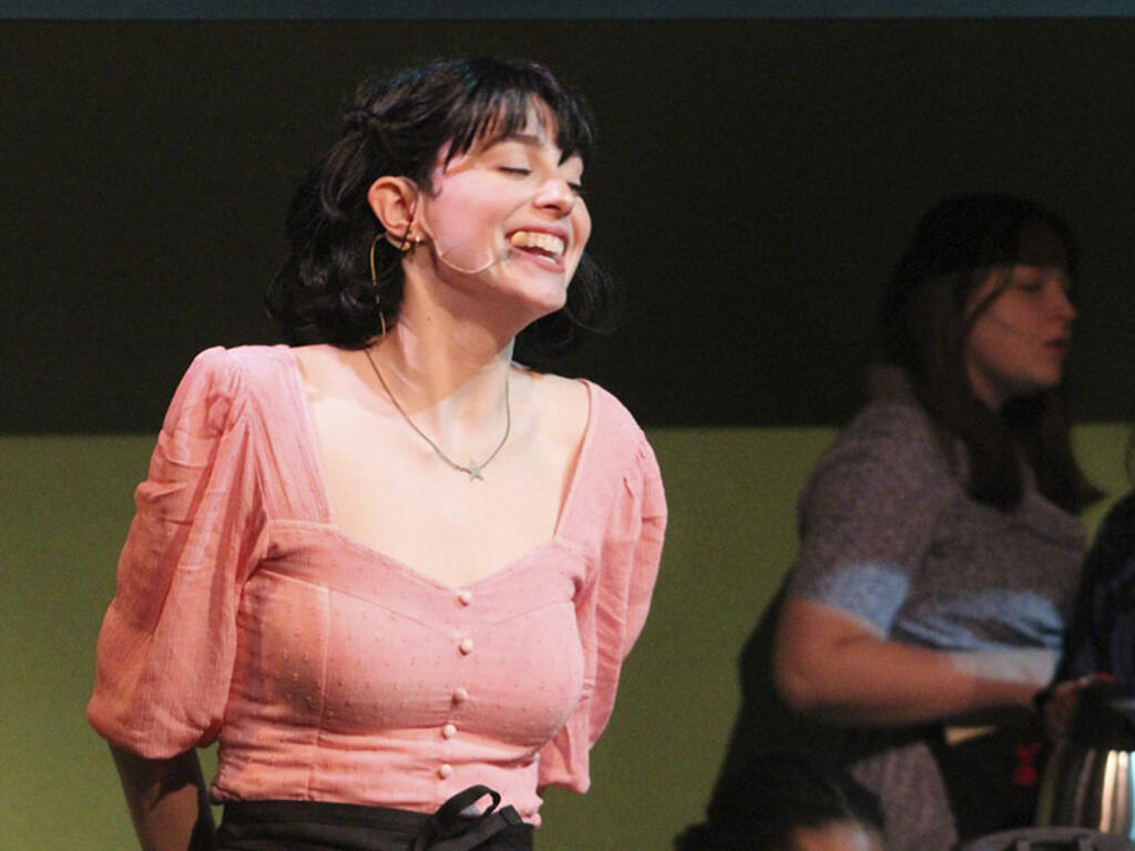 a young woman sings on stage