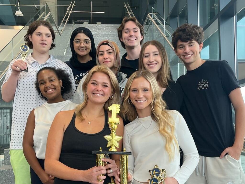 group photo of mock trial team, with members holding trophies