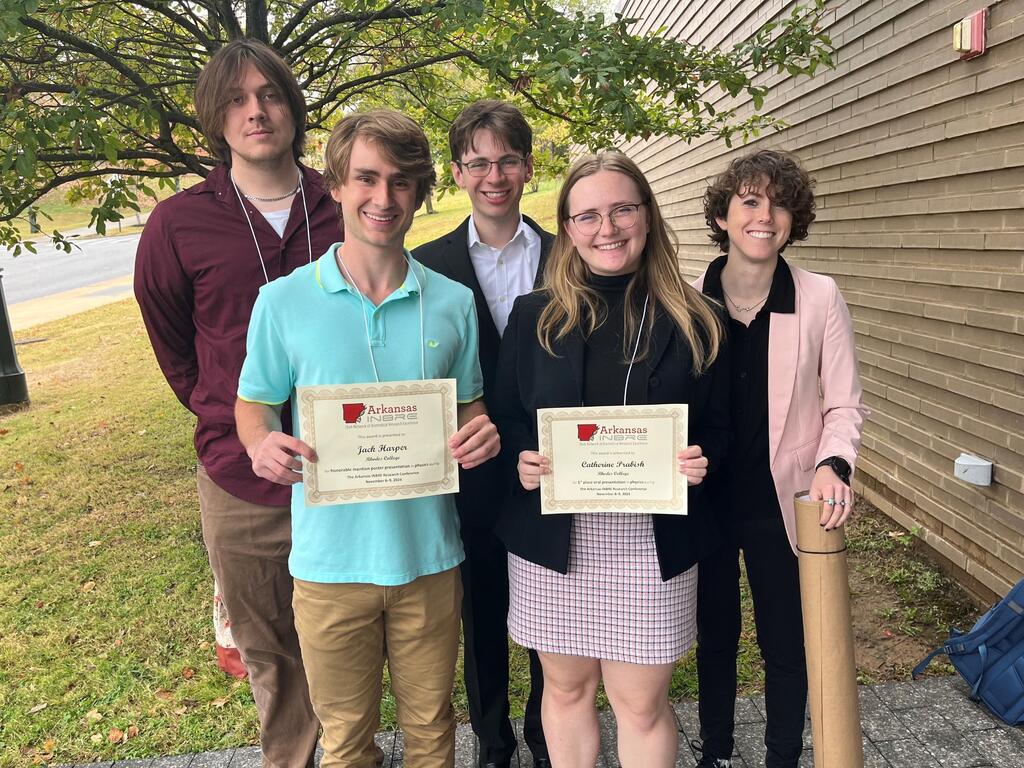 group image of Rhodes physics students, two of them holding certificates