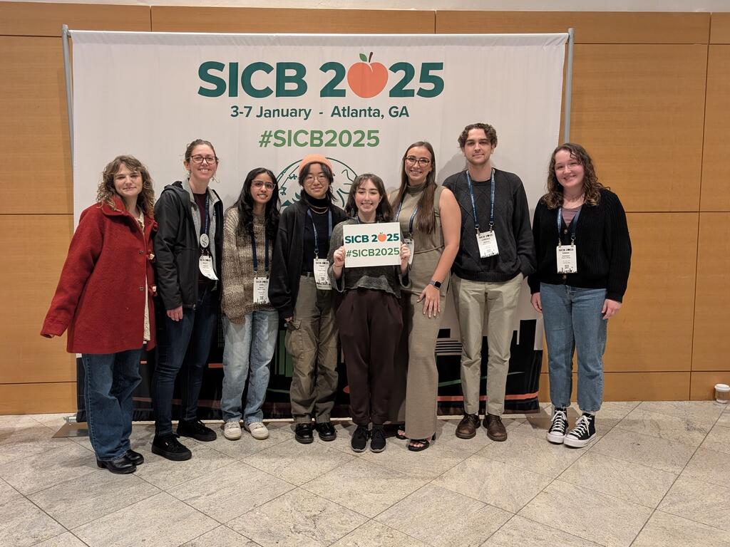 group image of Rhodes College research group standing in front of a science conference sign