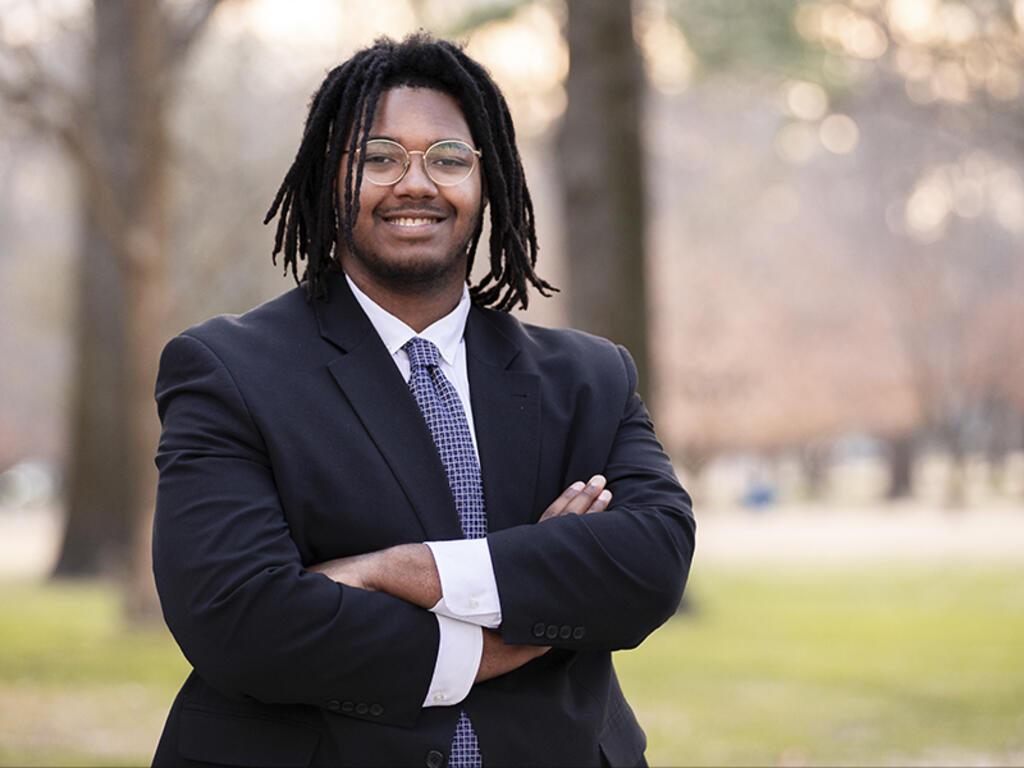 a young African American man with glasses smiles at the camera
