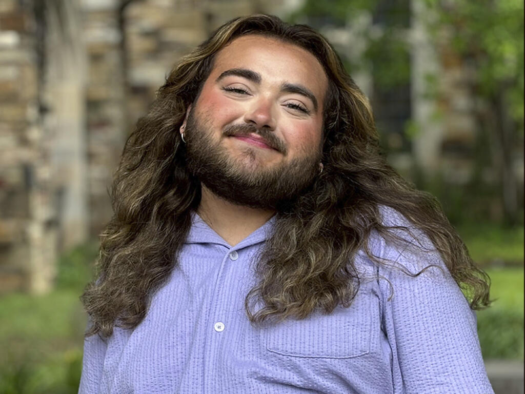 a young man with long brown hair and a beard