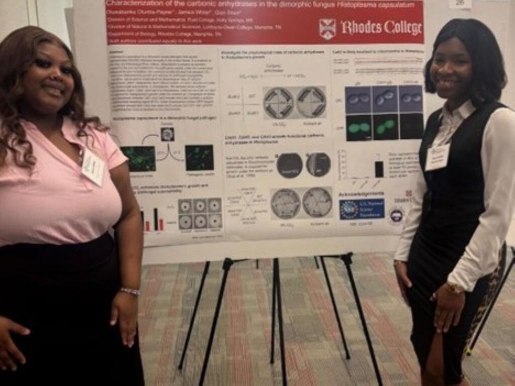 two students standing in front of a science poster