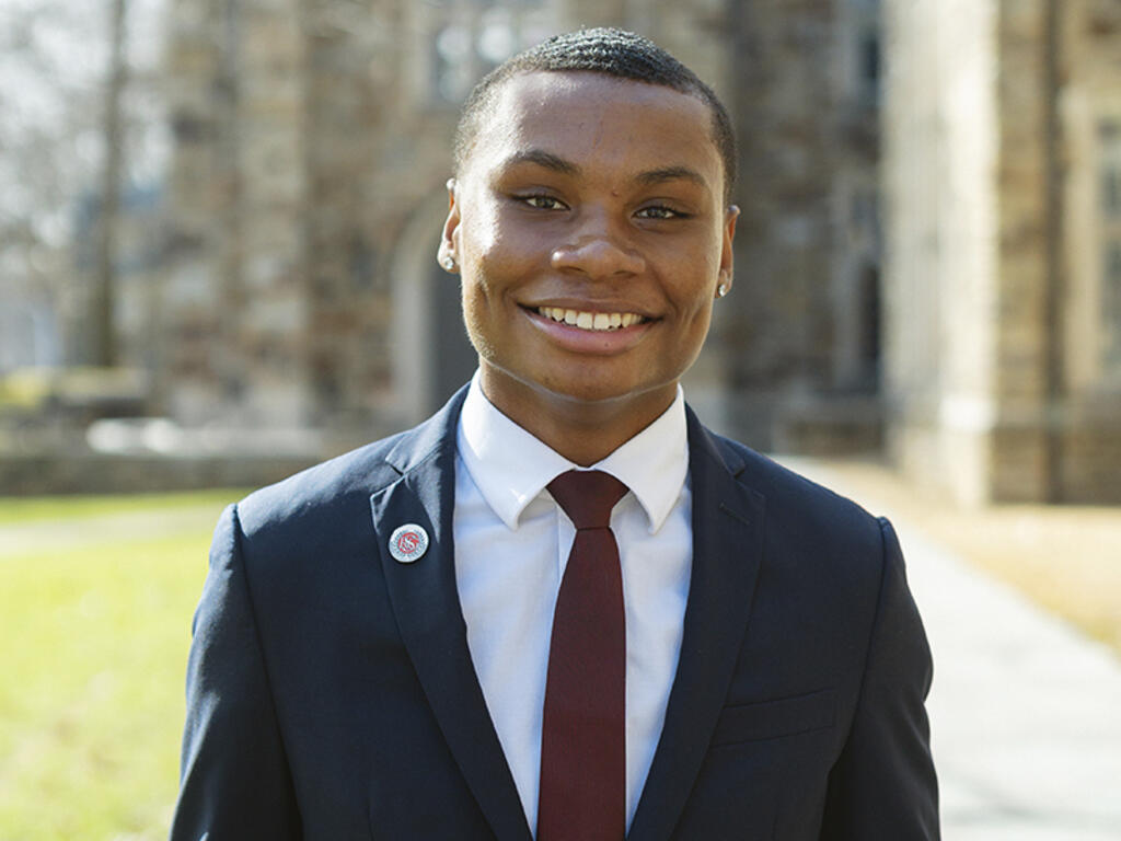 A young Black man smiles at the camera