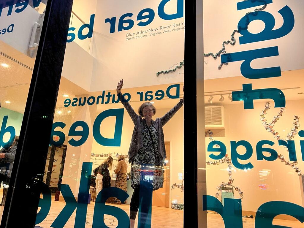 Gretchen E. Henderson in the window of the Dear Body of Water exhibit