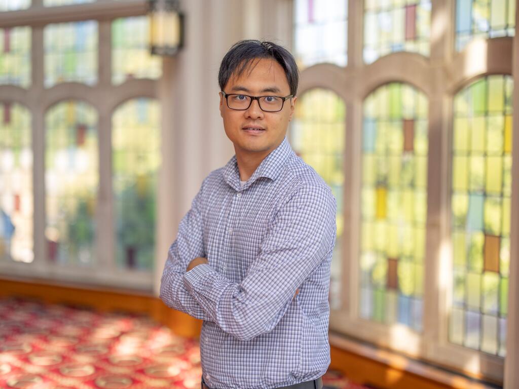 image of Casey Shin standing in front a stained glass window