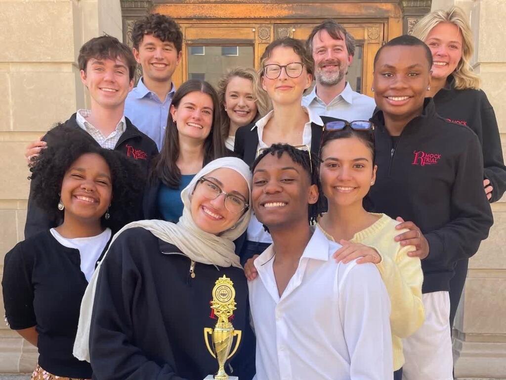 group image of Rhodes Mock Trial team, with of the members holding a trophy