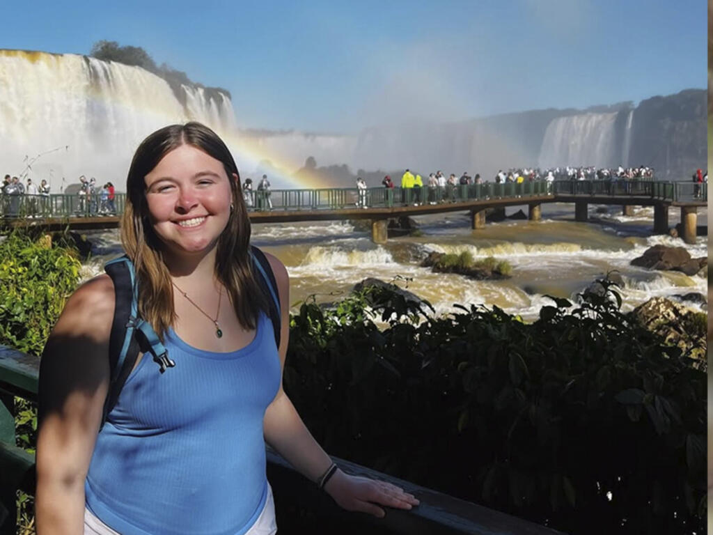 a young woman with a waterfall in the background