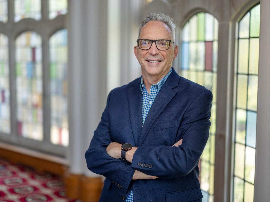 Image of Stephen Haynes standing in front of a stained glass window