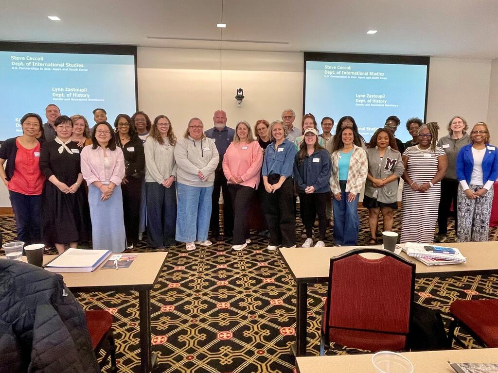 group photo of educators standing in a conference room, in front of screens