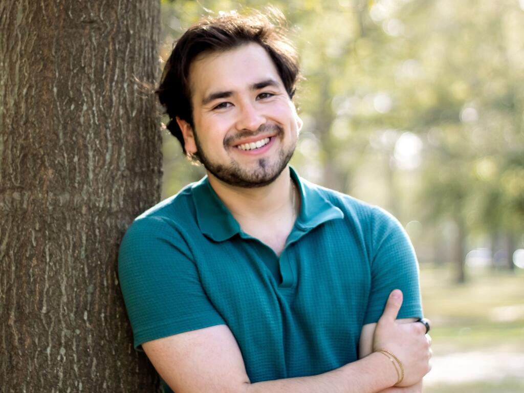 image of Tanner Chapman, smiling and leaning against a tree 