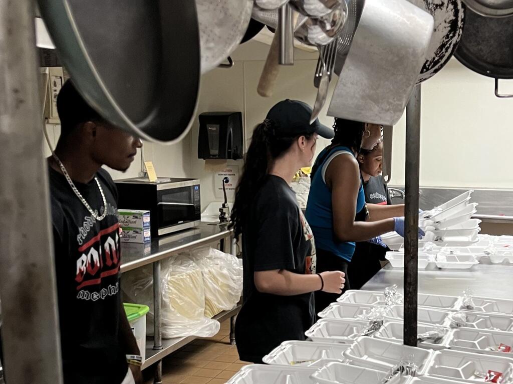 image of Rhodes College student in a kitchen preparing food trays