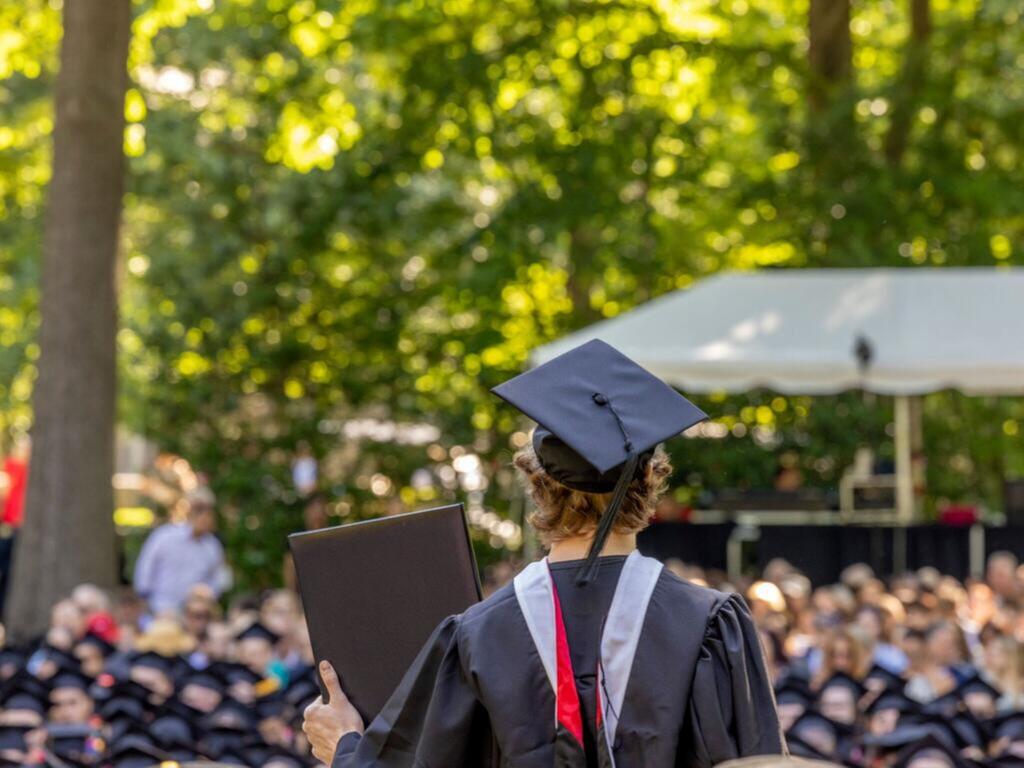 a Rhodes College graduate holding a diploma, in an audience of other graduates