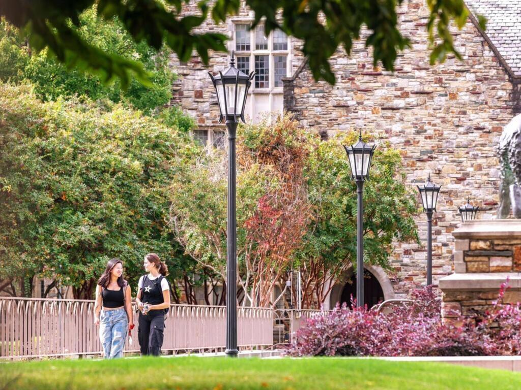 Two students walking among the trees on the Rhodes College campus