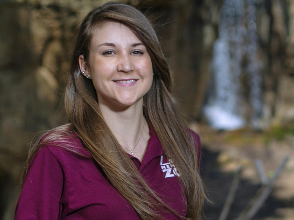 A close up of a brunette student with a maroon shirt on, smiling