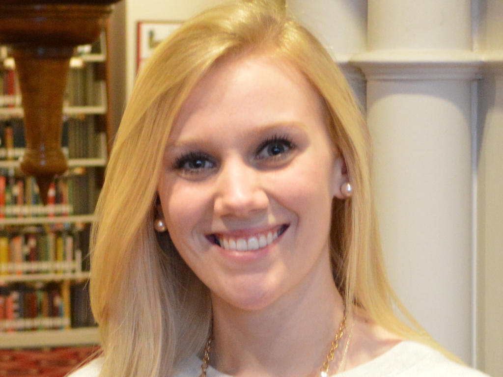 a headshot of a female student standing near a bookshelf