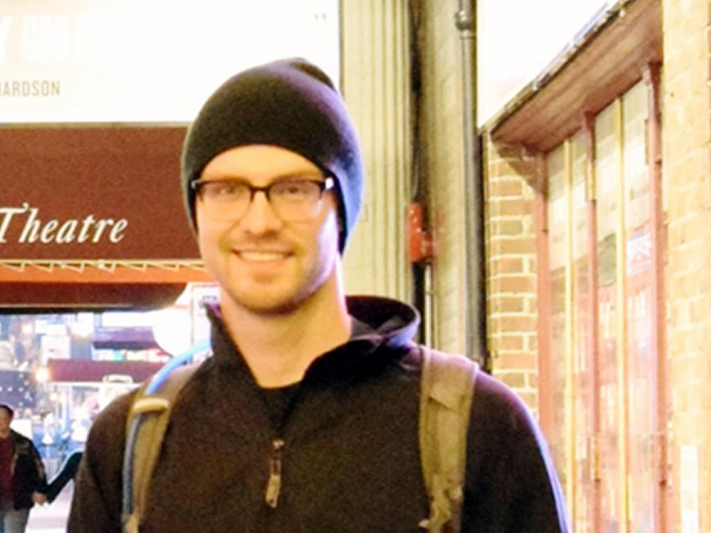 a young man smiling while wearing a beanie 