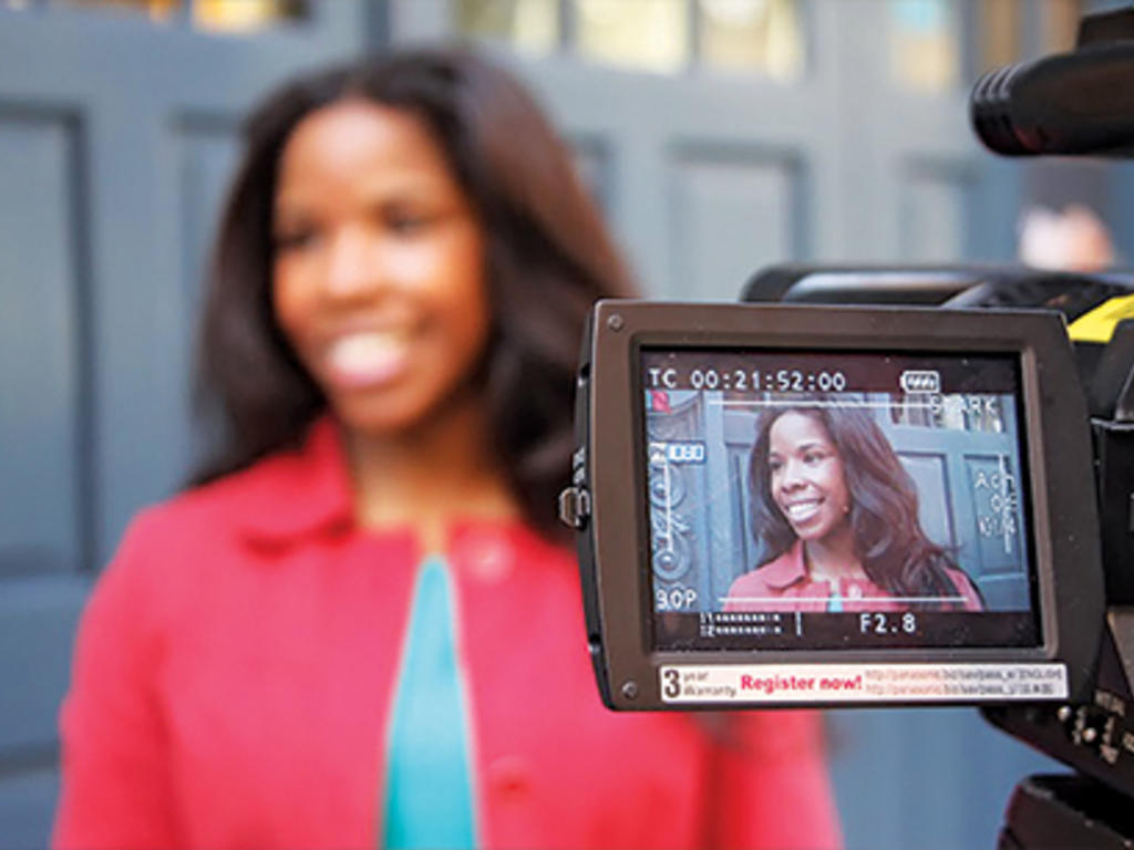a young African American woman is shown through the lens of a video camera