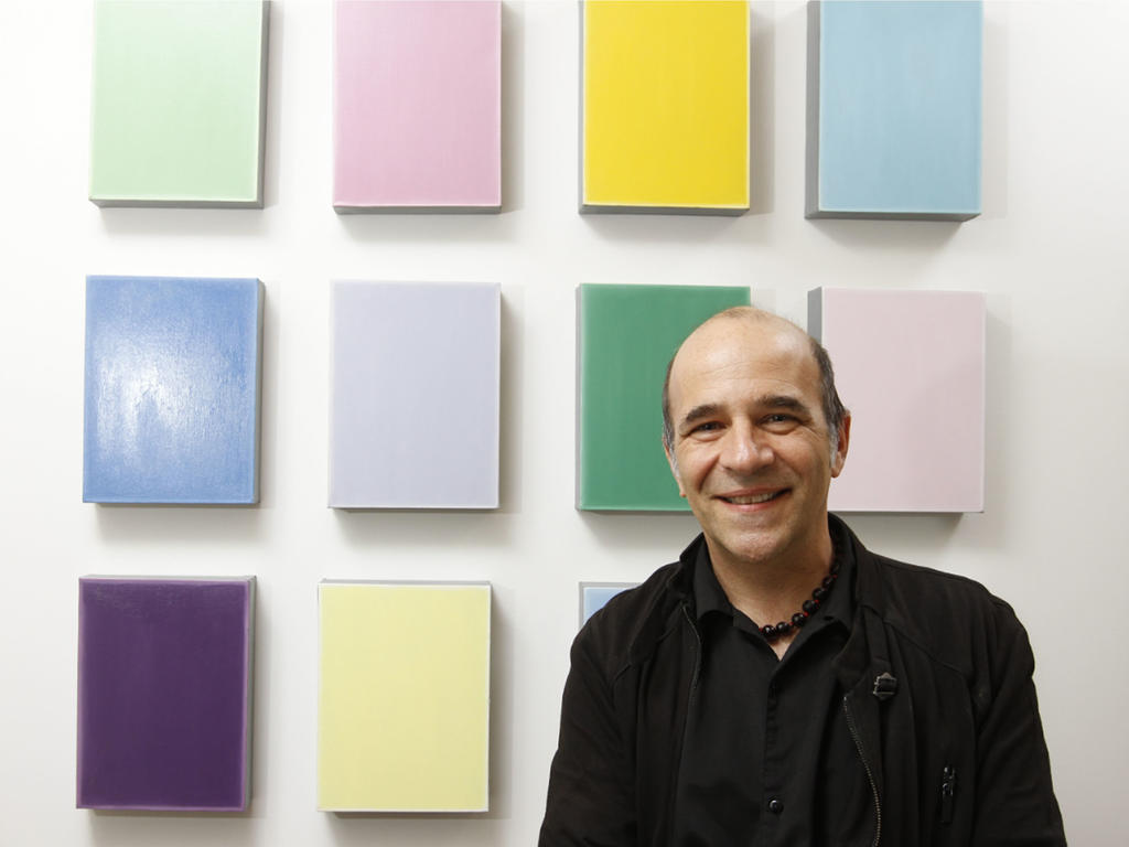 a male professor standing in front of multiple pieces of contemporary art