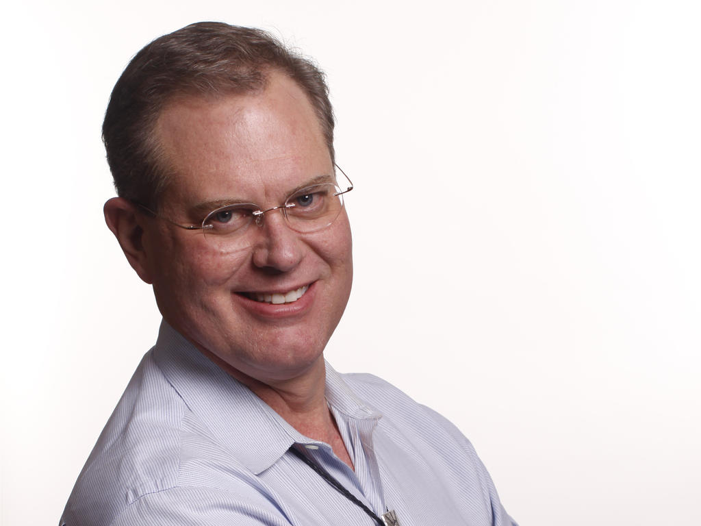 a middle-aged male smiling in front of a white background