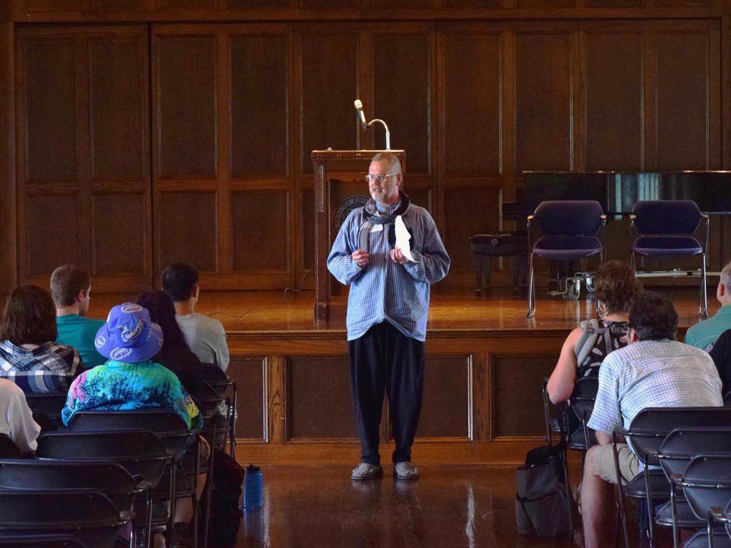 a white male professor giving a speech to an audience in a wooden board room