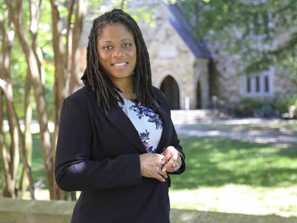  an african-american, middle-aged woman standing in front of an out-of-focus academic building
