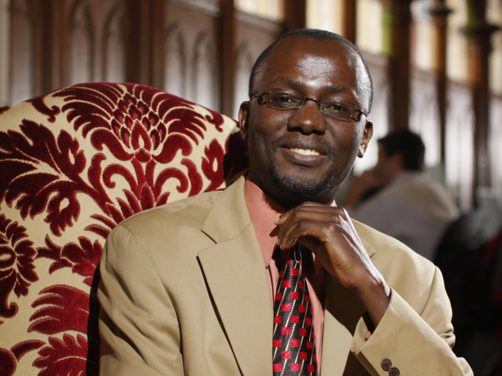 an African American professor sitting on a couch in the library