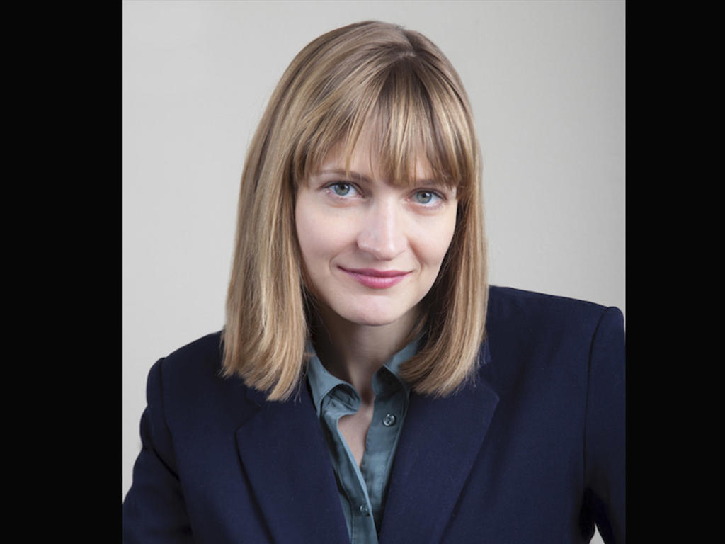 a middle-aged woman's headshot on a tan background