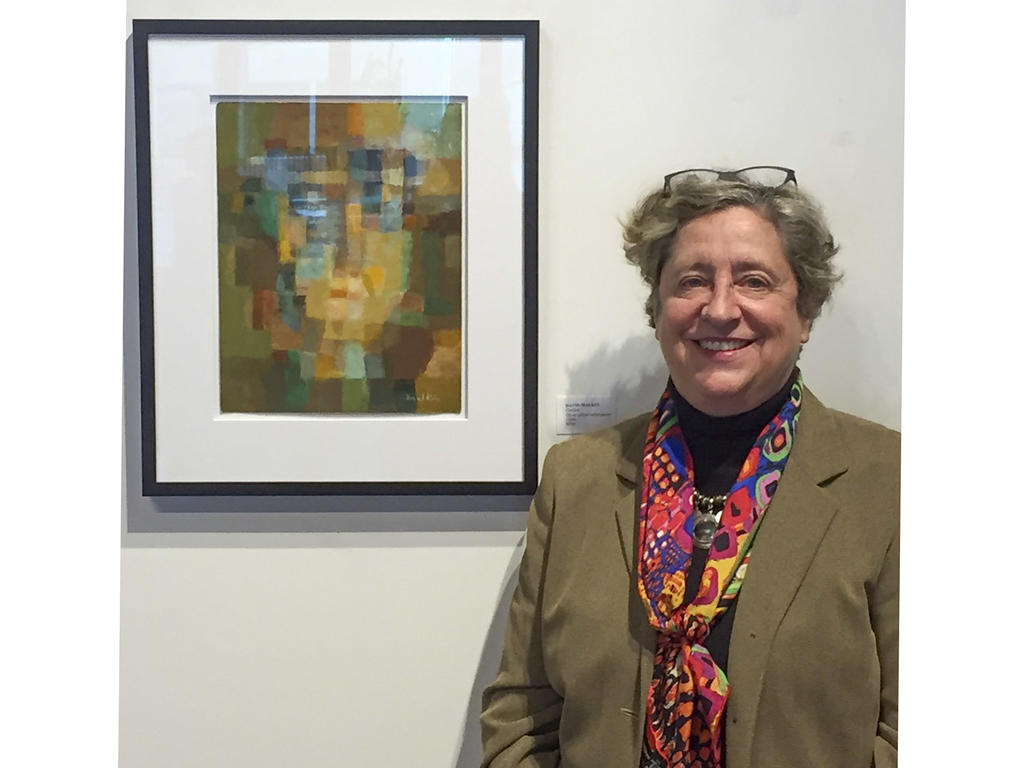 an older white woman standing near a framed work of art