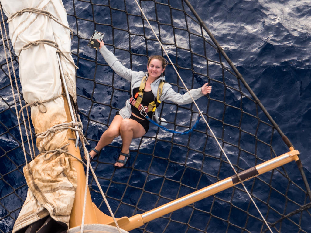 a young female hanging out on the bow of a boat in the middle of the ocean