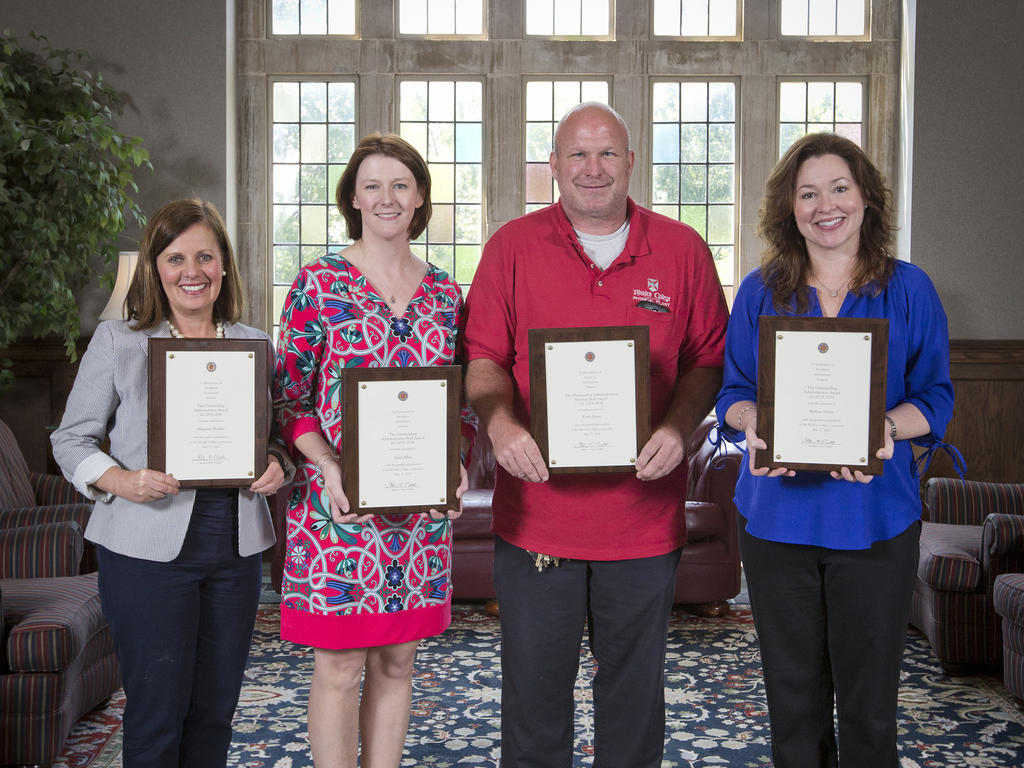 four faculty members proudly holding their framed awards 