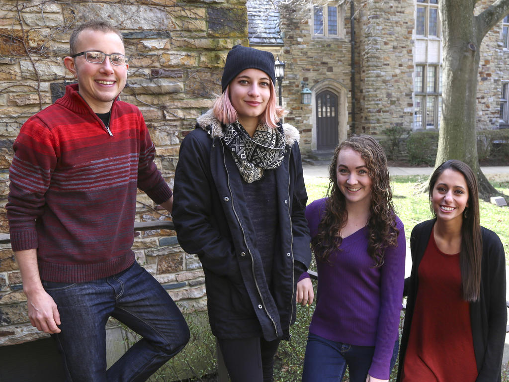 three female students with their male professor posing on a staircase outside of an academic building at Rhodes College