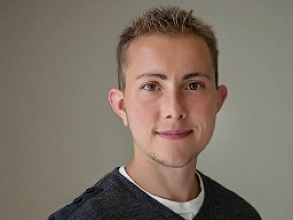 a headshot of a young male on a grey background