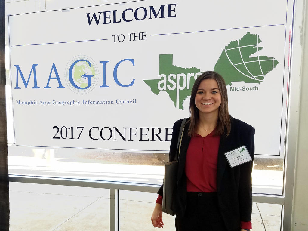 student standing in front of a conference welcome sign