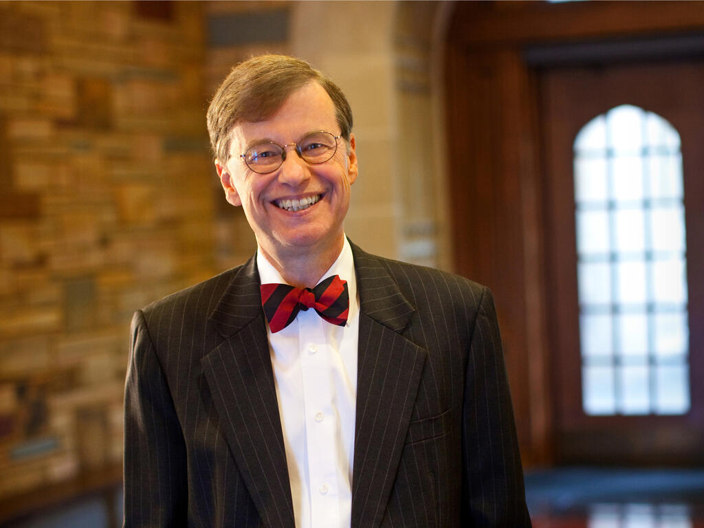 an older white male wearing a red bow tie smiling in the library